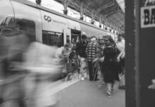 Jak infrastruktura kolejowa zmienia turystykę: dworce jako bramy do regionów i atrakcji Czarno-biała scena z pasażerami na dworcu kolejowym w Lizbonie