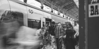Jak infrastruktura kolejowa zmienia turystykę: dworce jako bramy do regionów i atrakcji Czarno-biała scena z pasażerami na dworcu kolejowym w Lizbonie