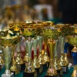 Złote puchary ustawione na stole, symbolizujące sukces i osiągnięcia
