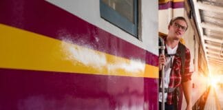 Jak przygotować się do pierwszej samodzielnej podróży pociągiem od A do Z Młody mężczyzna z plecakiem wsiada do pociągu na miejskim dworcu