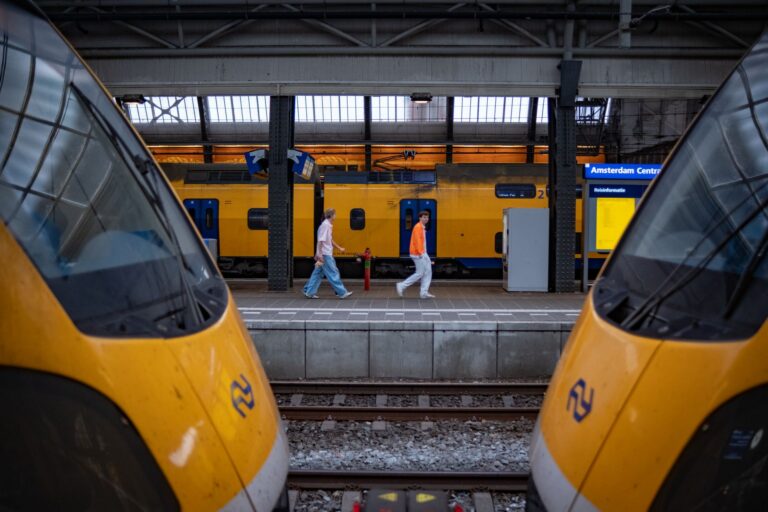 Pasażerowie na dworcu Amsterdam Centraal przy żółtych pociągach NS